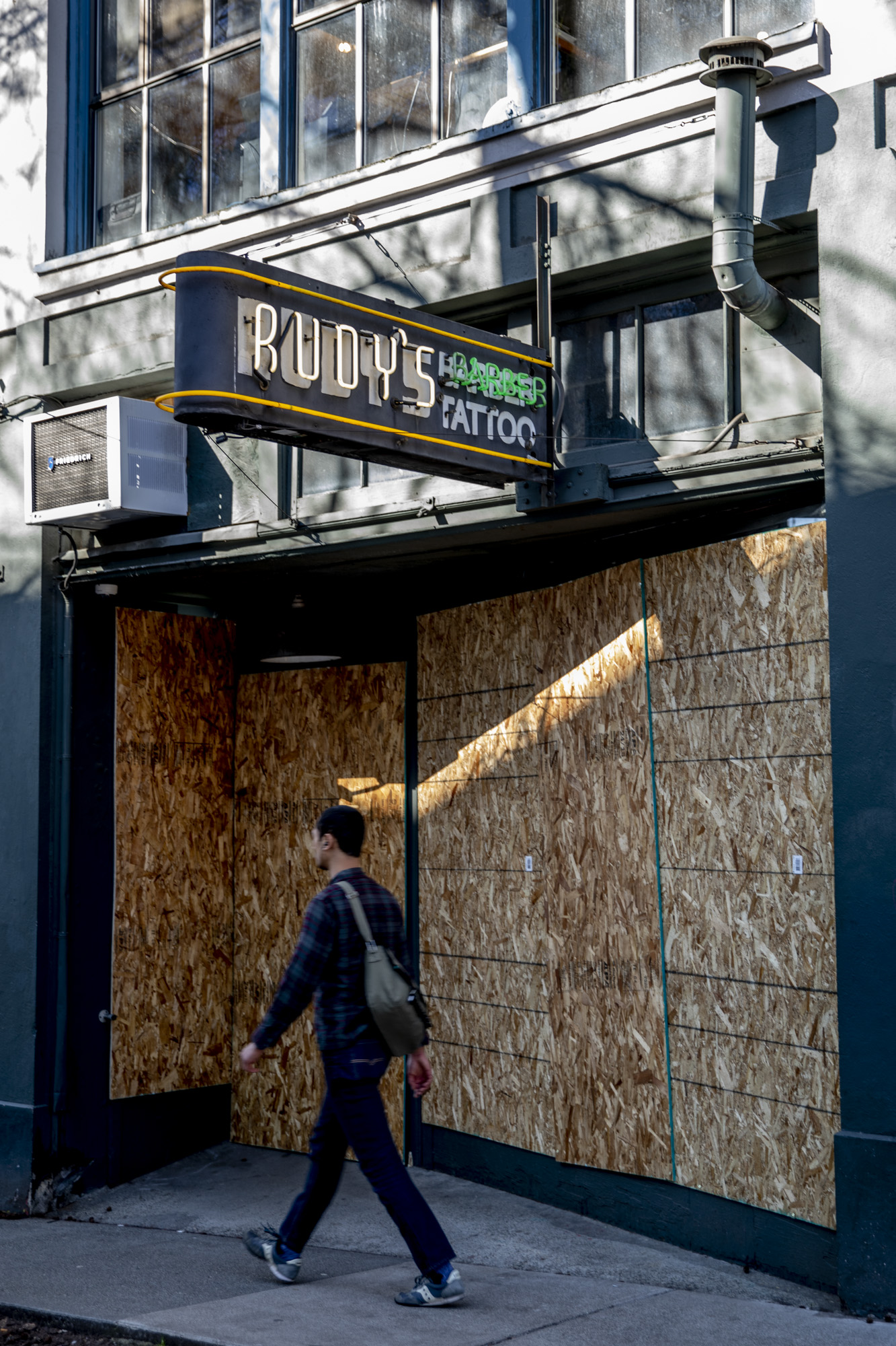 Man walks in front of boarded Rudy's