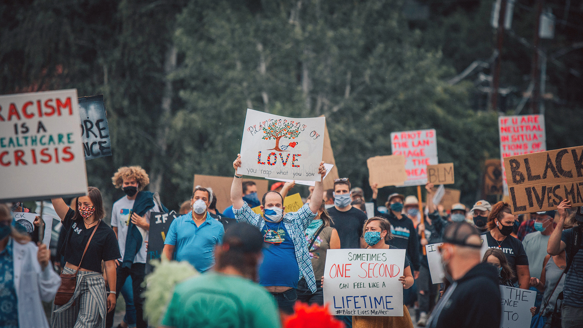 A crowd of people stand with signs