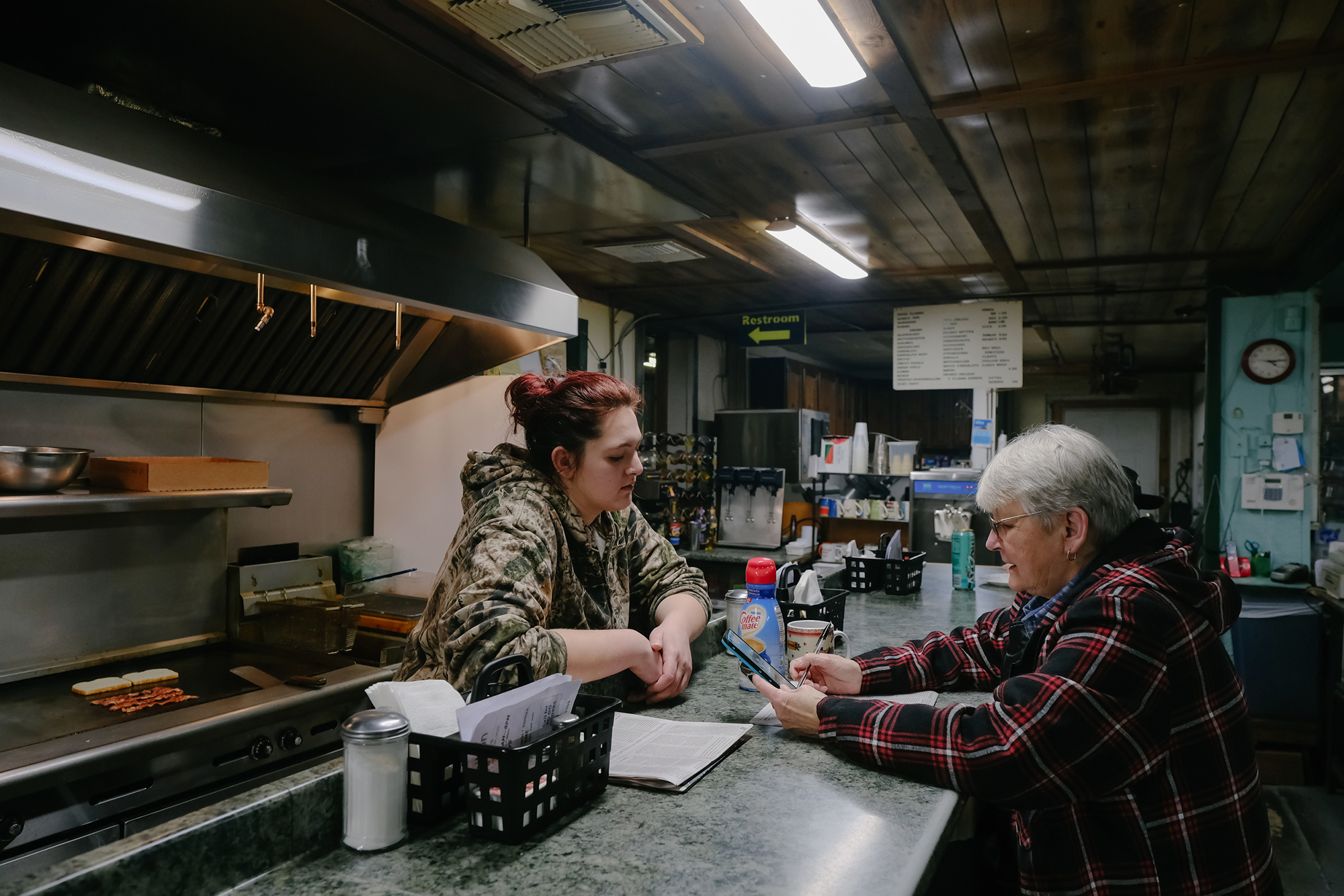 Two women sit inside a diner