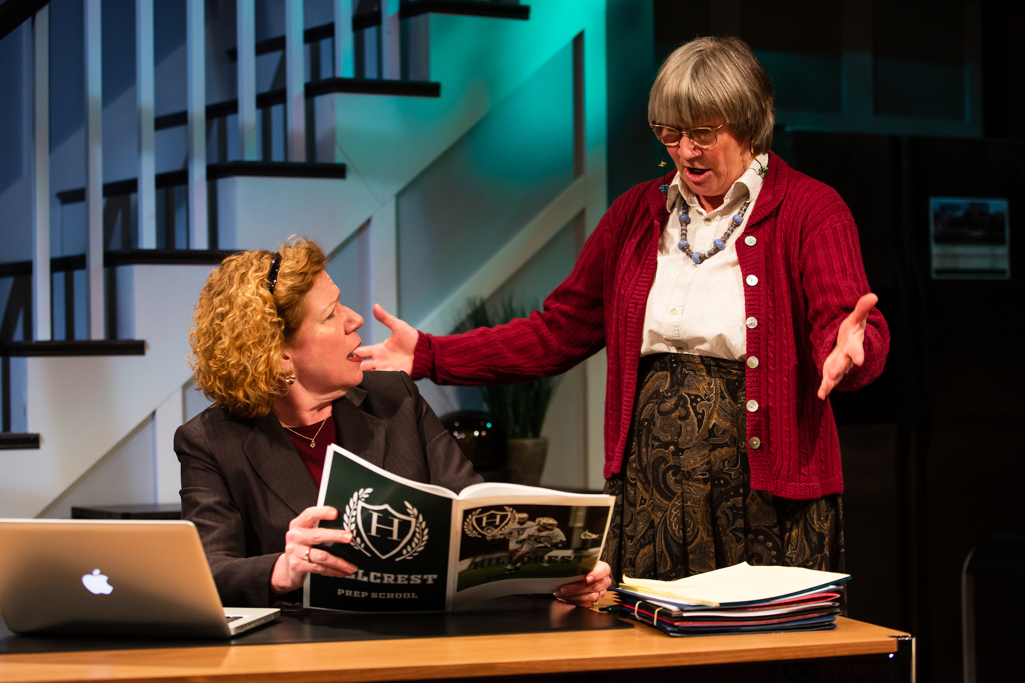 two women on stage, arguing over a magazine