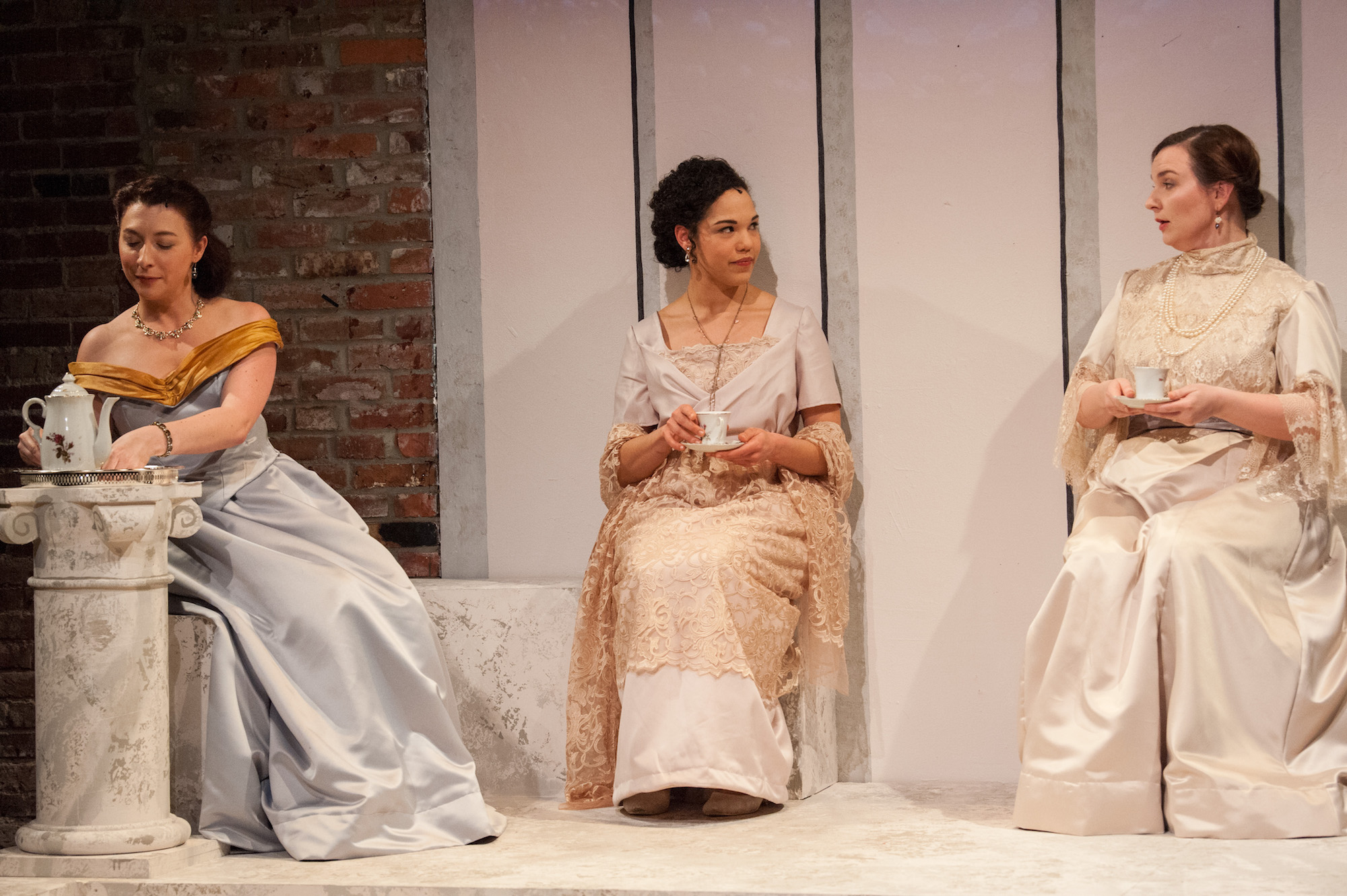 three women in period costumes having tea