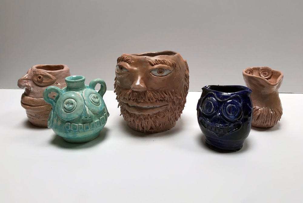 collection of pottery mugs with faces on them