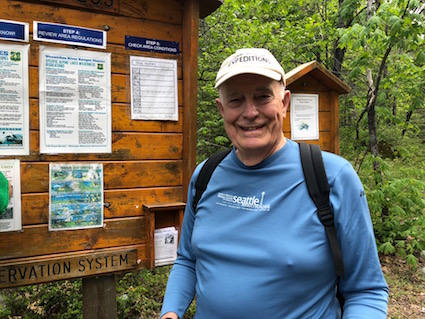 Dan Evans in front of a trailhead information sign