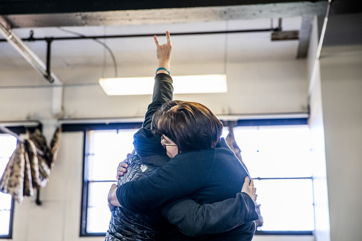 Two dancers hug while one does horns with her hand