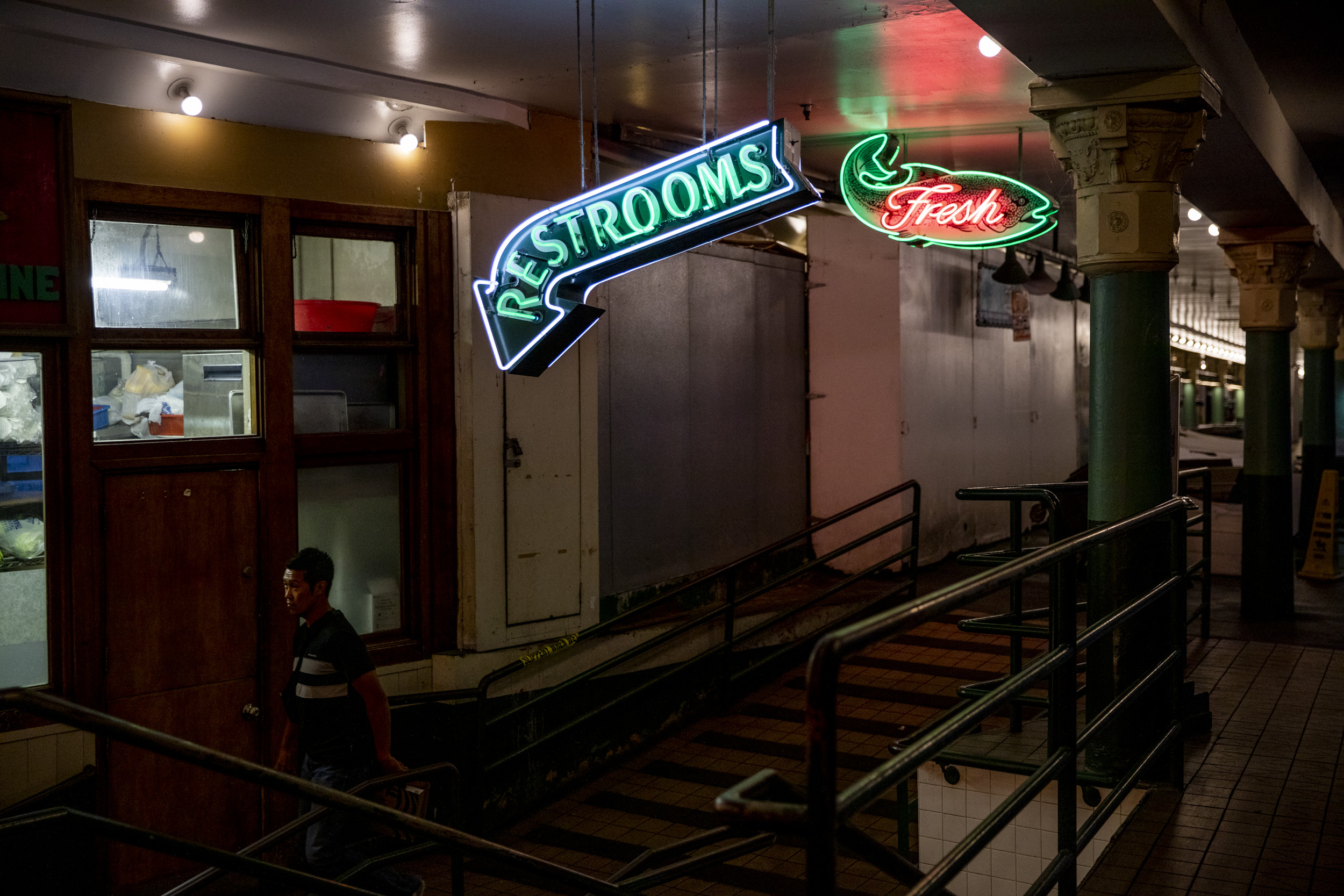 man walks under neon signs 