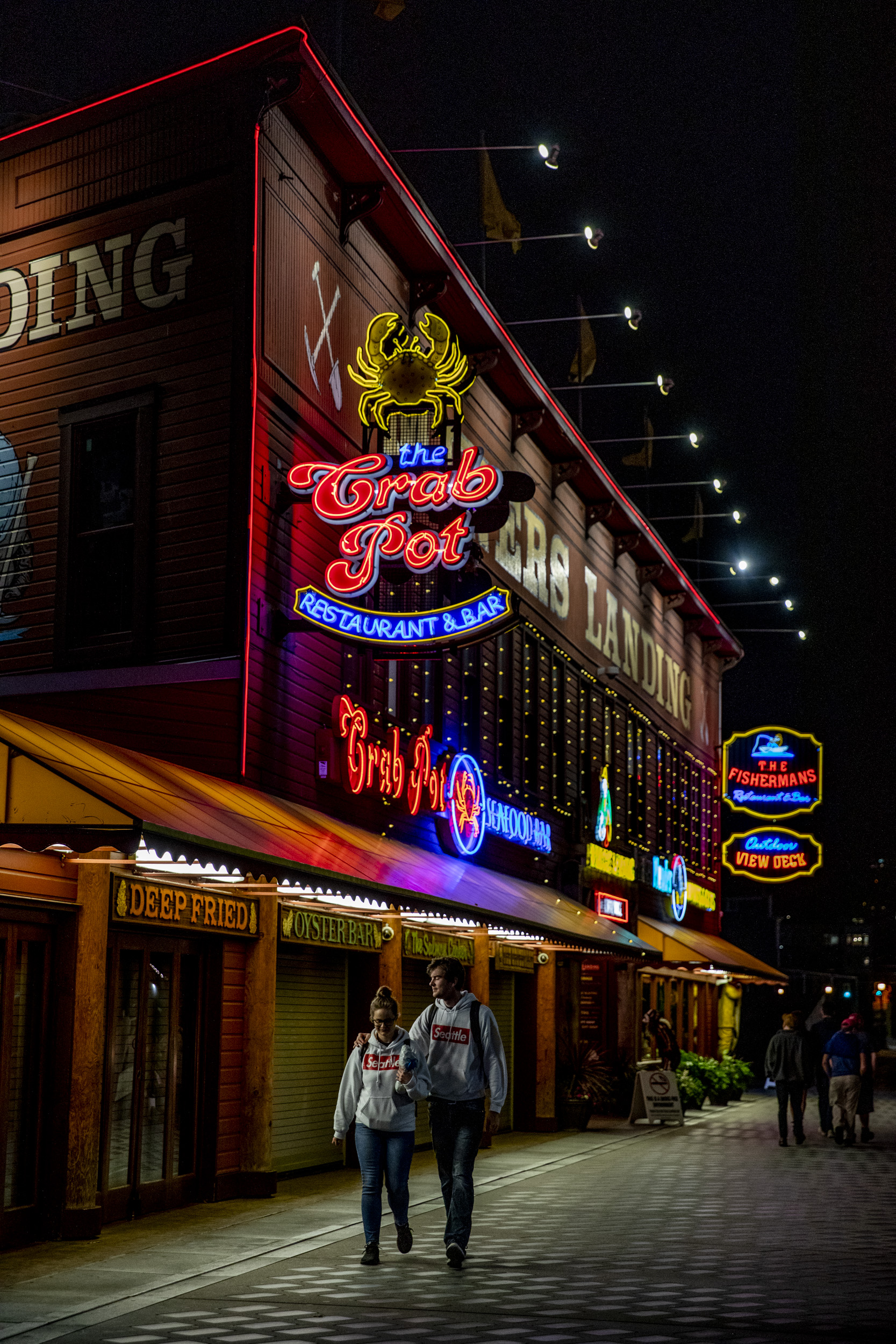 two people walk along the Seattle boardwalk at night