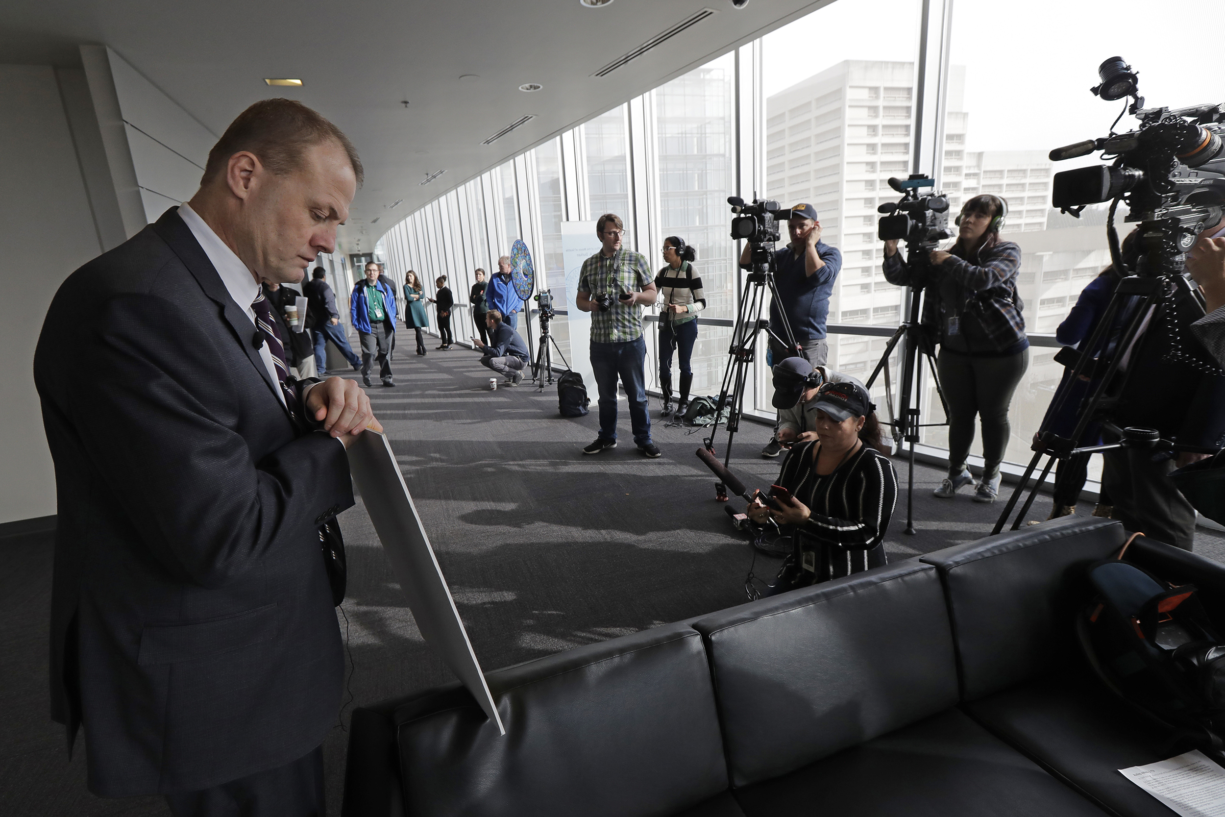 Tim Eyman holds a sign as cameras film him in city hall