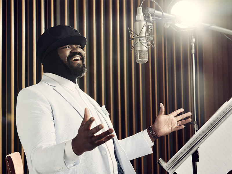 a man in a white suit singing into a microphone