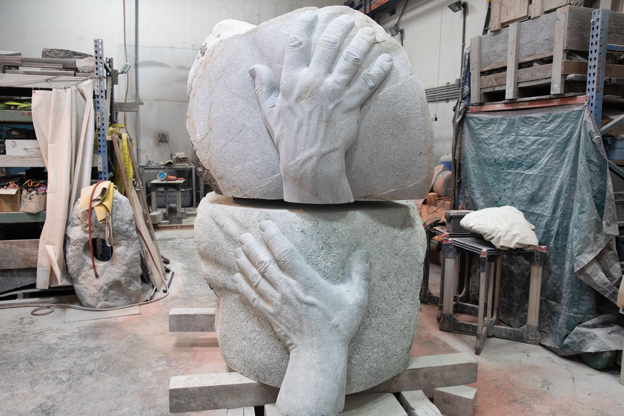 two boulders, with giant hands carved into them, stacked