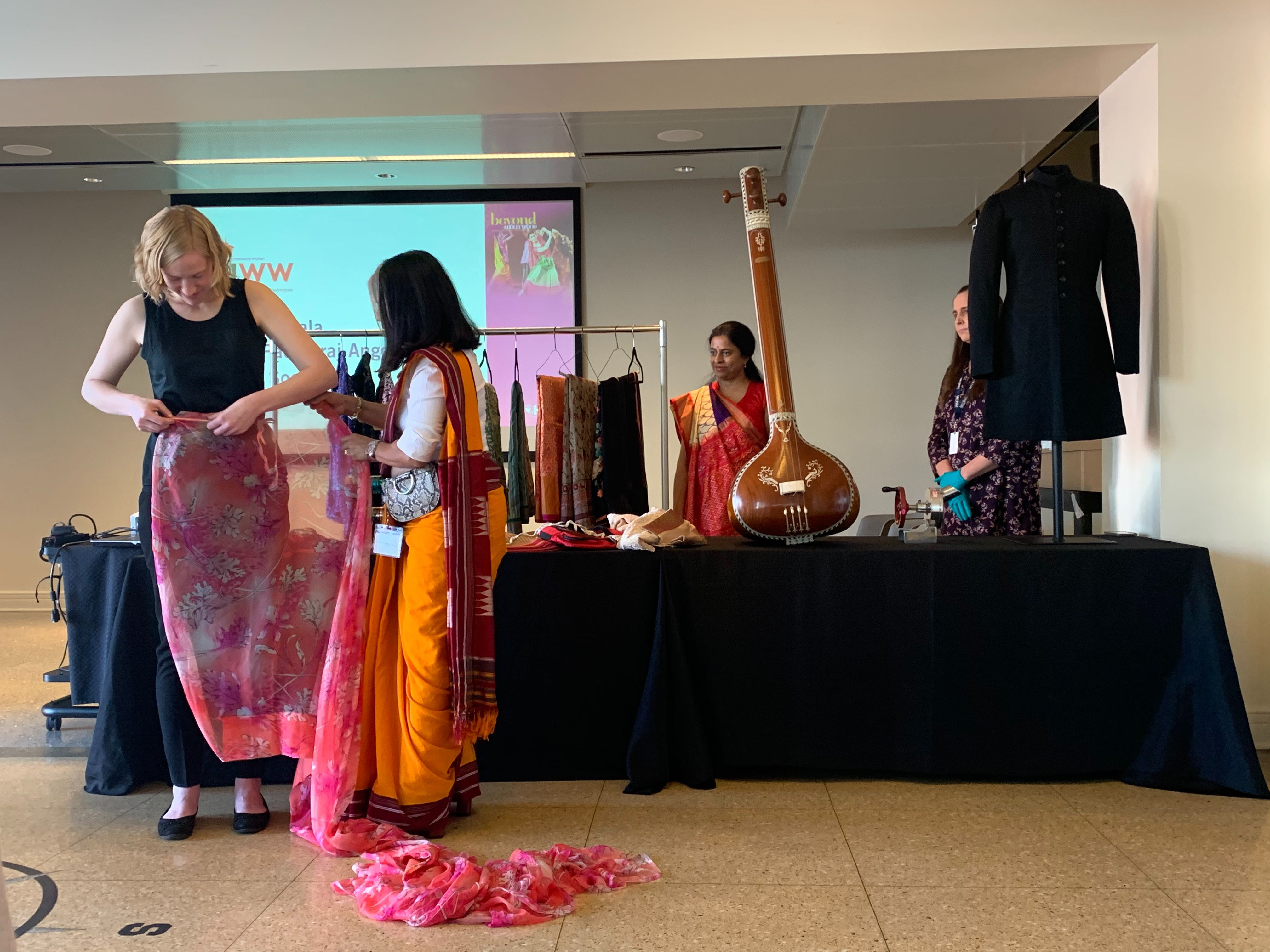 a woman shows another woman how to drape a sari