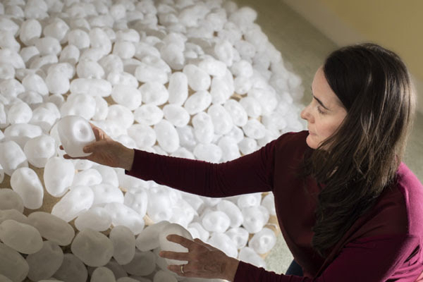 a woman sits with glass blown potatoes