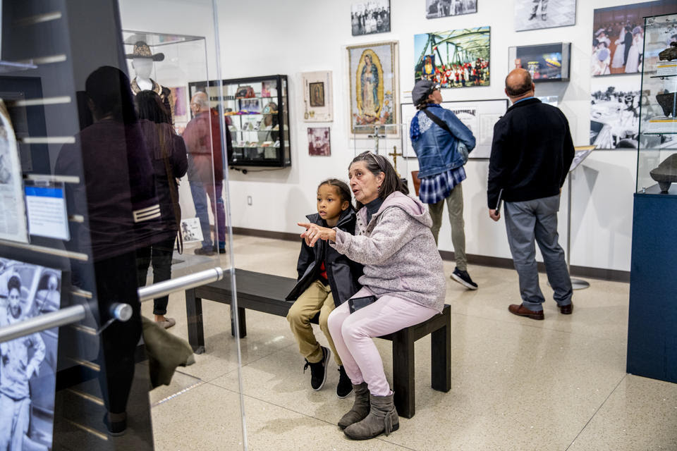 a woman shows an exhibit to her grandchild