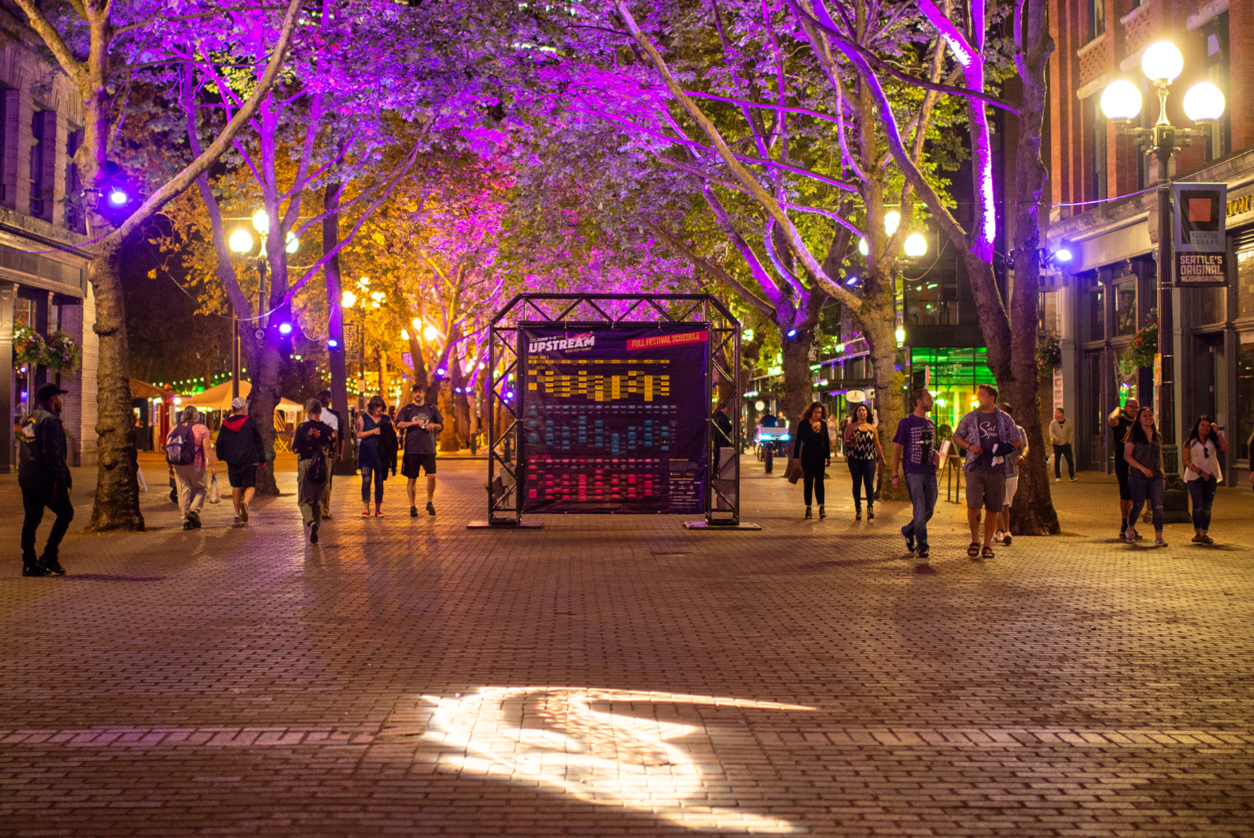 Upstream Music Festival attendees walk from one showcase to another along Occidental Avenue South near midnight on Saturday, June 2nd, 2018, during the festival's second year. 