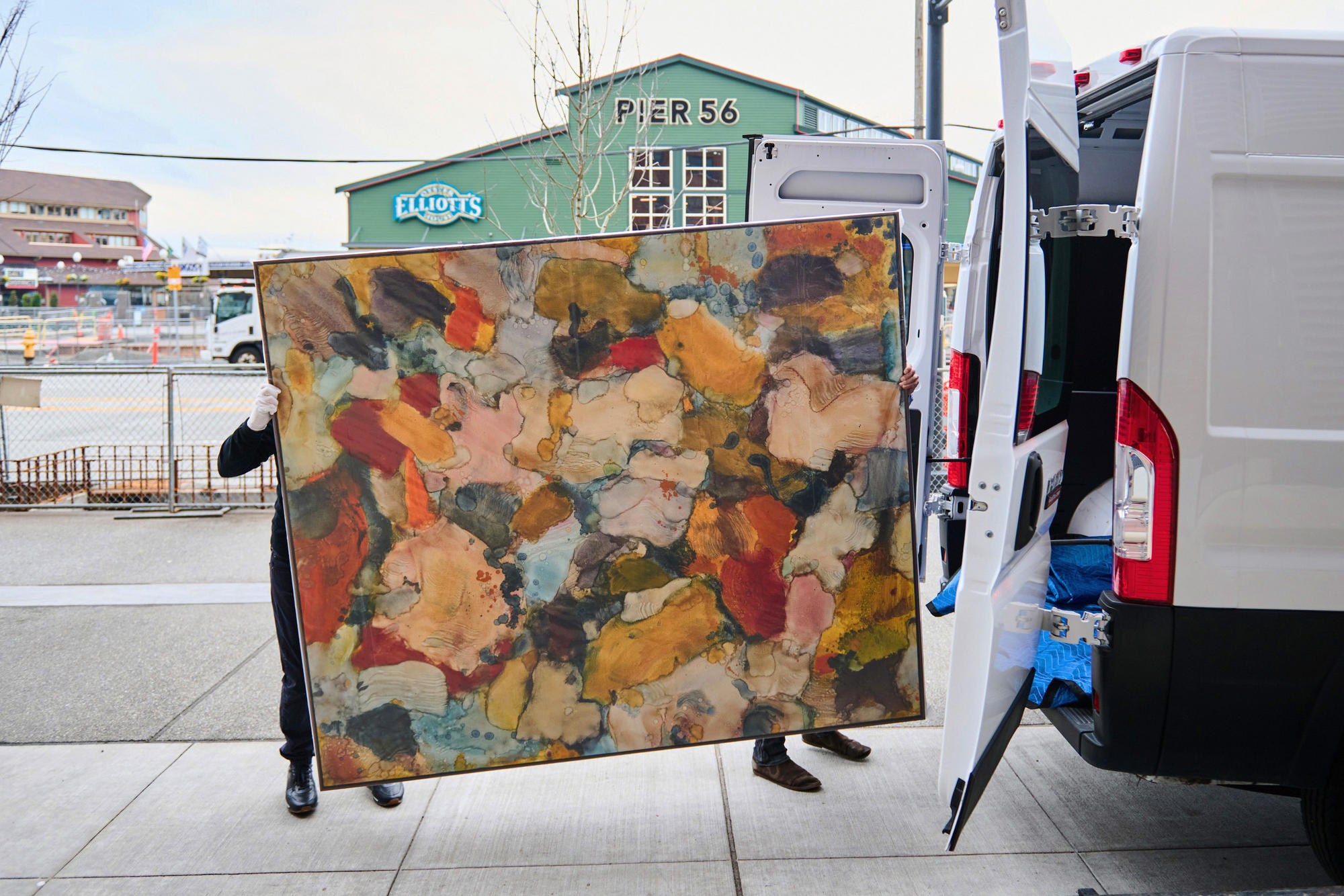 two people move a painting into a white van