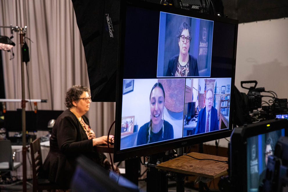 A monitor in a studio shows three guests