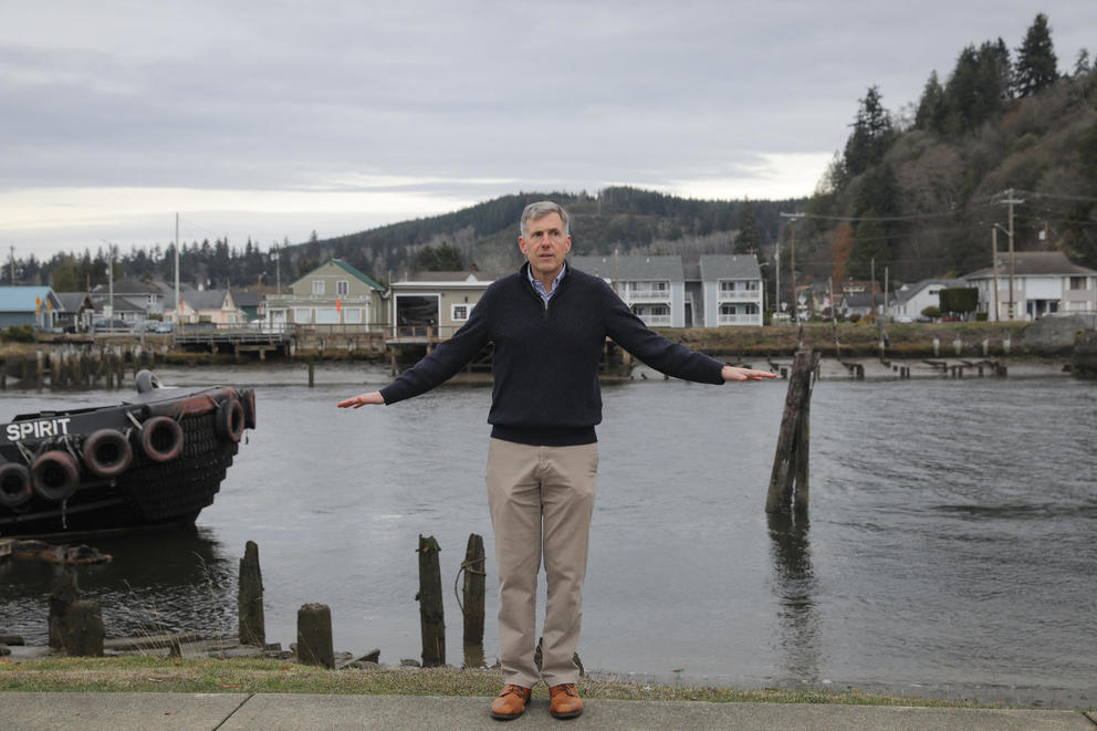 A man on the edge of a body of water holding his hands at waist level