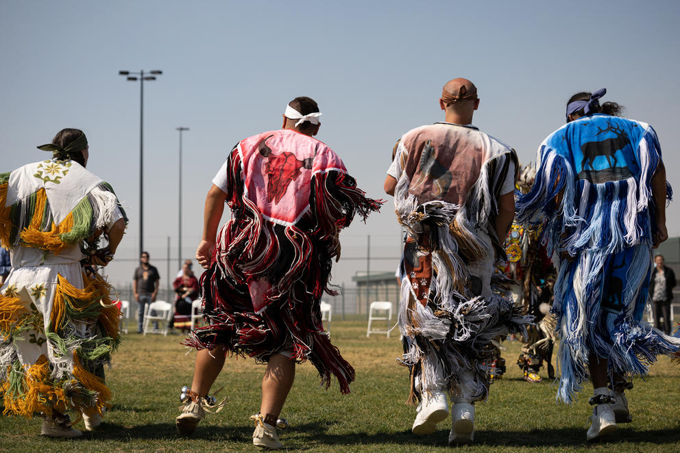 Four people dancing in regalia