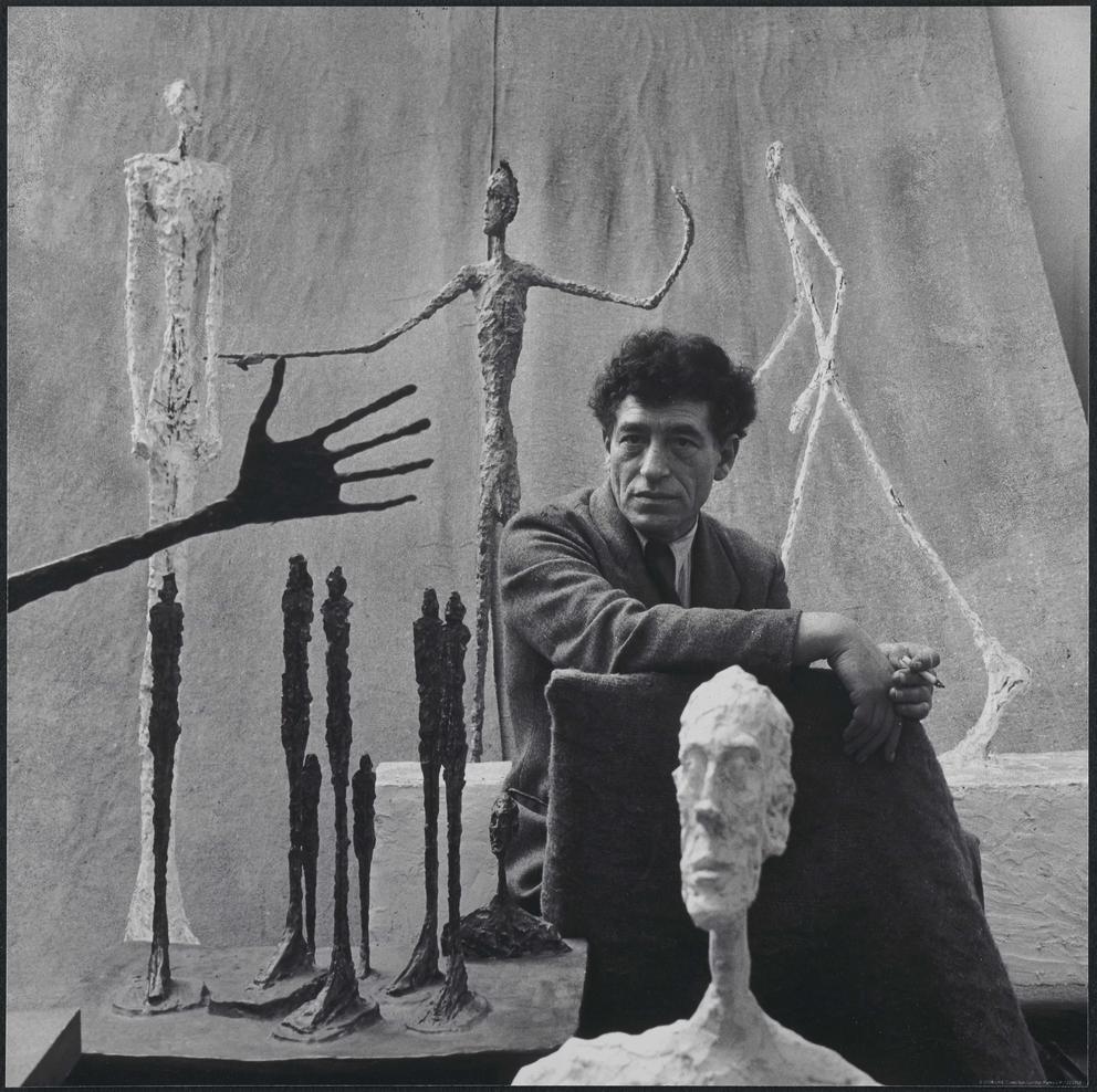 An artist in his studio, black and white photo featuring his slender artworks in metal and plaster