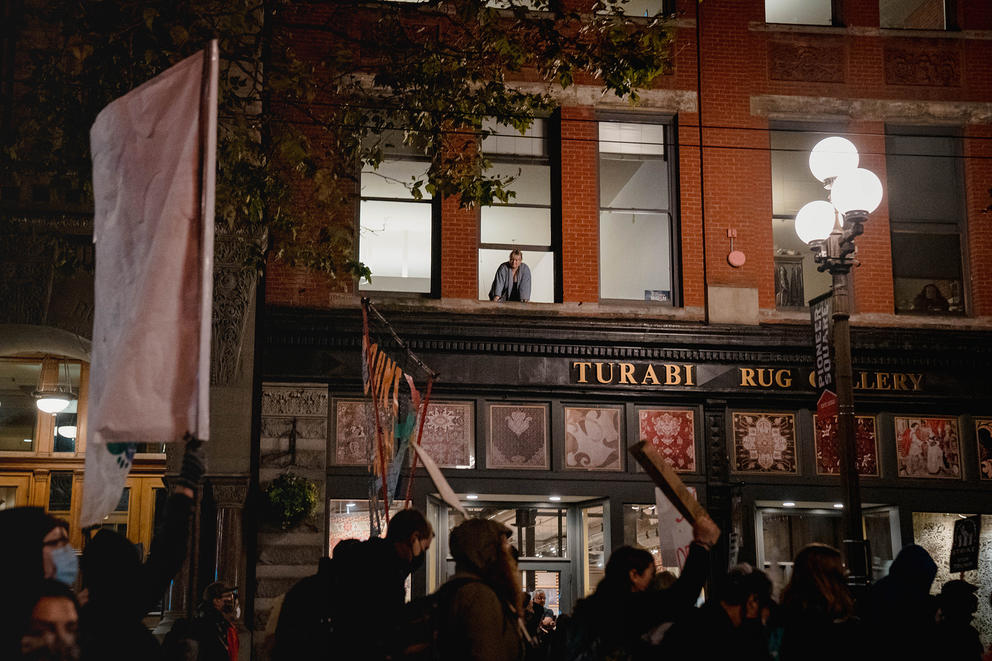 Onlookers watch as hundreds of demonstrators march through Pioneer Square