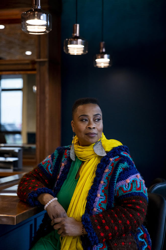 woman with yellow scarf and large earrings under three hanging lamps