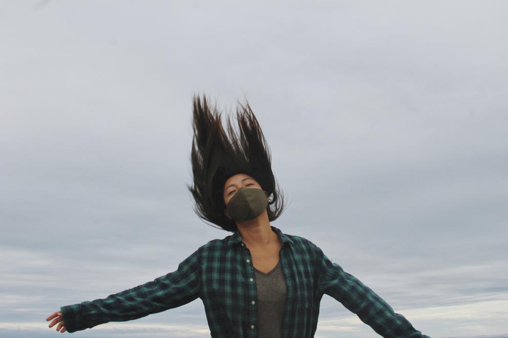 Person with mask jumping in the gray air