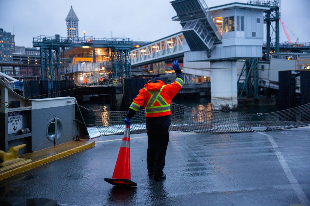 A ferry worker moves a traffic cone out of the way on a ferry