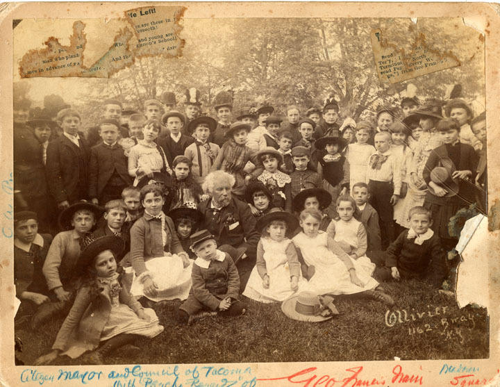 an 1800s photo of children surrounding an older man