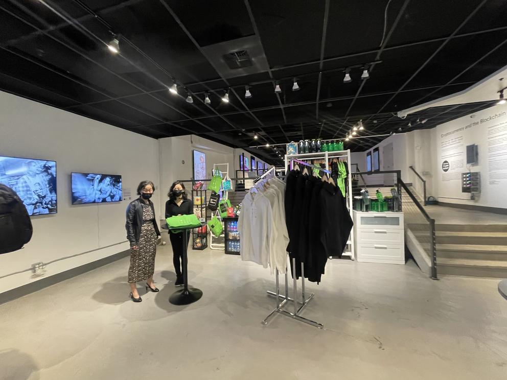 a lobby with white walls and floors, a black ceiling, and a rack of sweatshirts