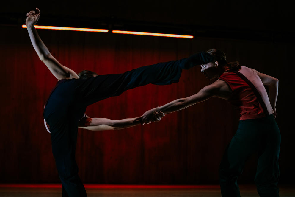 Two dancers in front of red drop coth 