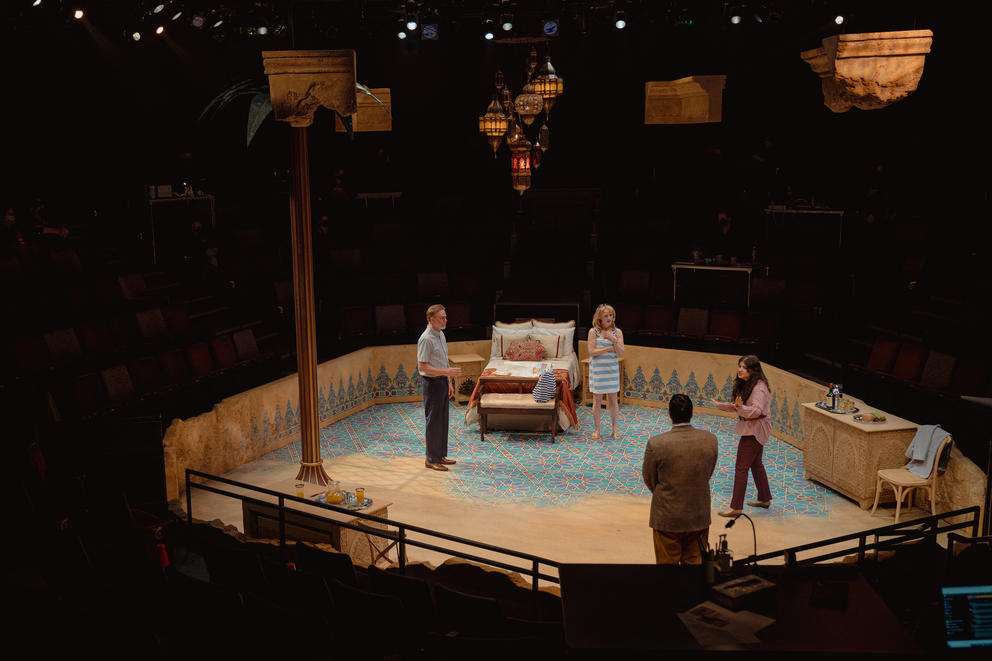 four actors seen from a distance, rehearsing a play on stage