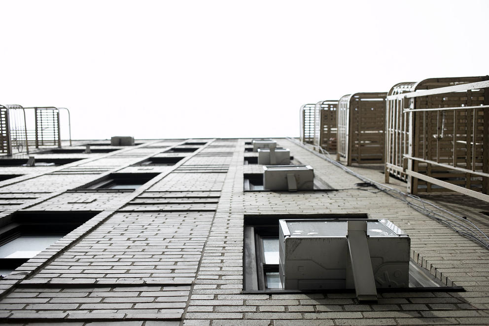 A view from below of air conditioning units on the outside of an apartment building