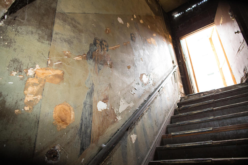 A view looking up the Louisa Hotel staircase where old murals line the walls