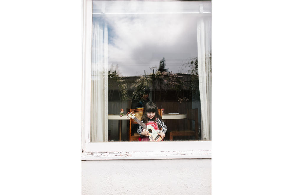 Girl shows off her guitar from behind the window