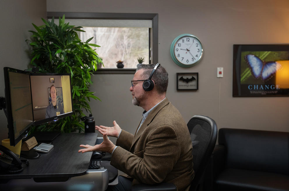 Wayne Pollard sits at a computer talking to Dr. Iles-Shih on the screen