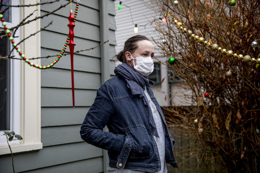 Heather Frey stands outside a building, with hands in pockets, wearing mask