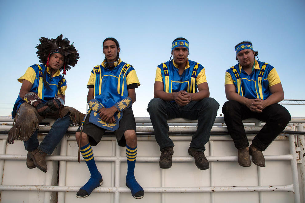 Four people in traditional costumes sit on a ledge