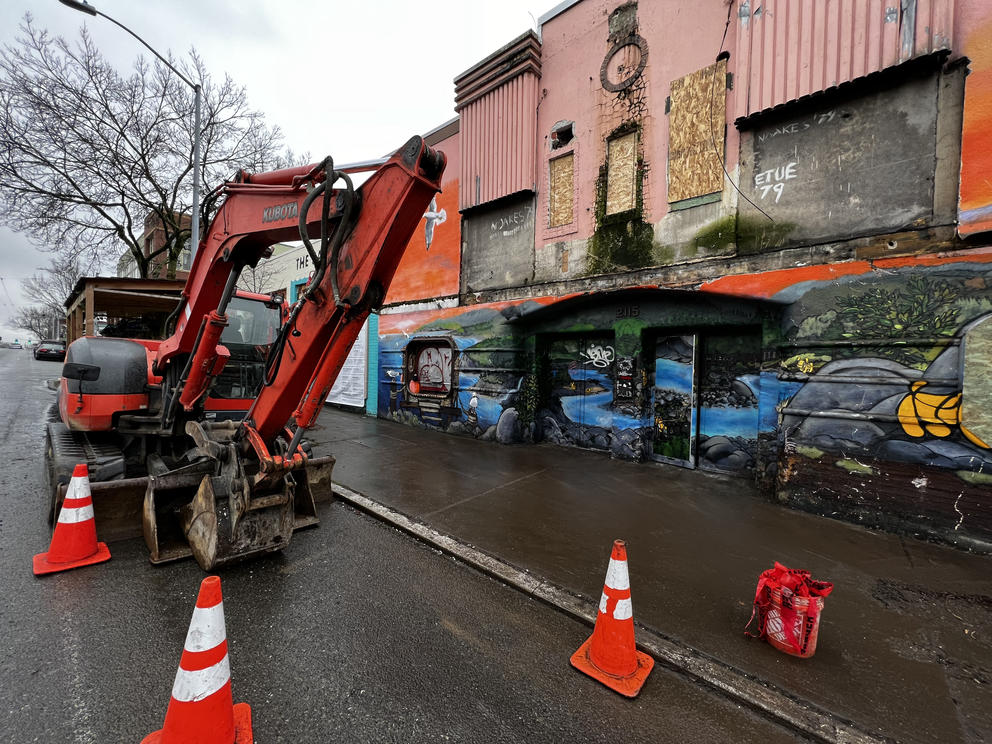 a construction digger and the battered remains of a retro pink movie theater