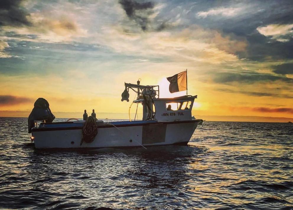 A boat on the water backlit by the sunset