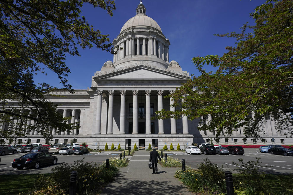 Trees flank a view of the Washington State Capitol, with blue sky behind the building and its dome