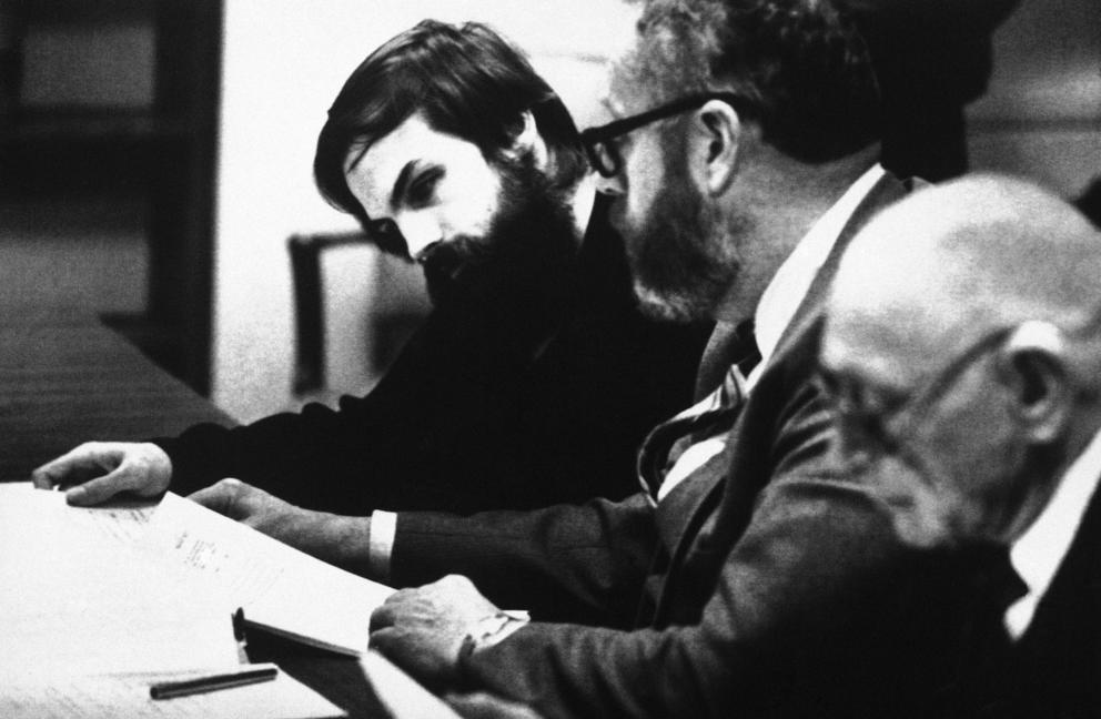 Three men at at table looking at papers