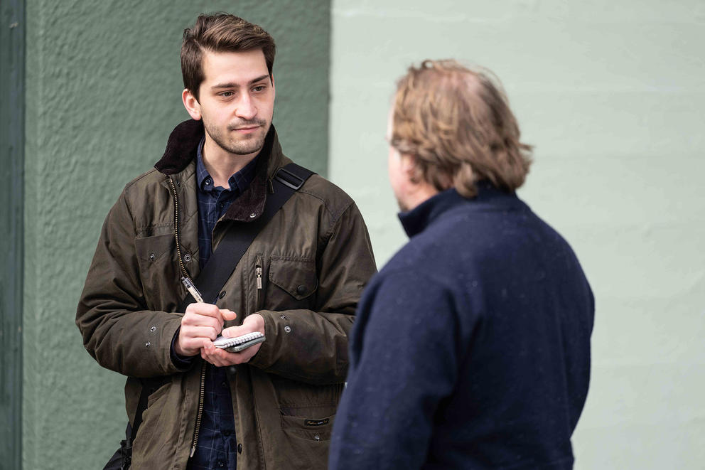 Block writes in a notebook as he conducts an interview