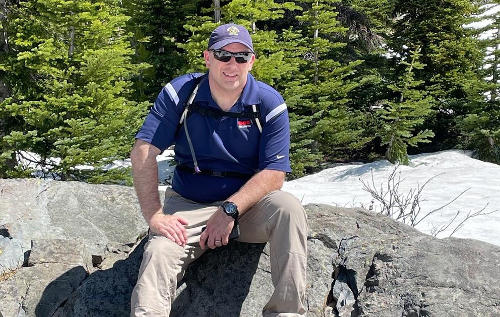 Terry Carter is shown in a hat and sunglasses, sitting on a rock formation