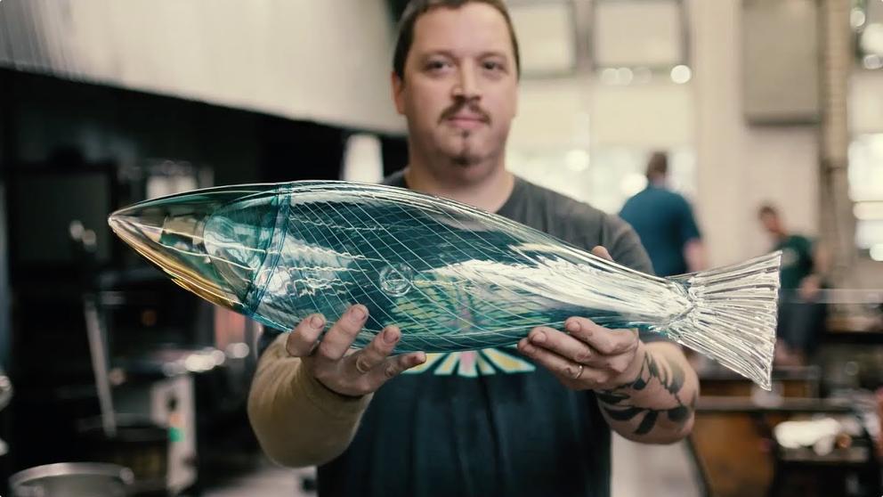 a man holds up a glass fish