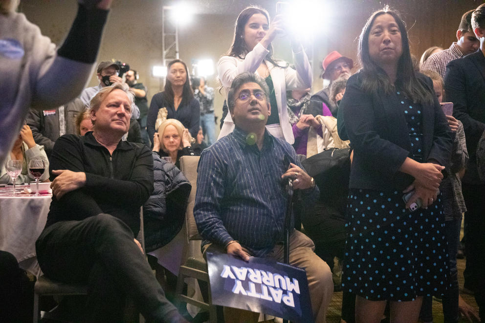 A crowded room of people, one holding a sign in support of Patty Murray