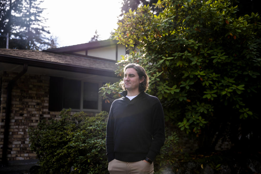 A man stands outside in front of his home