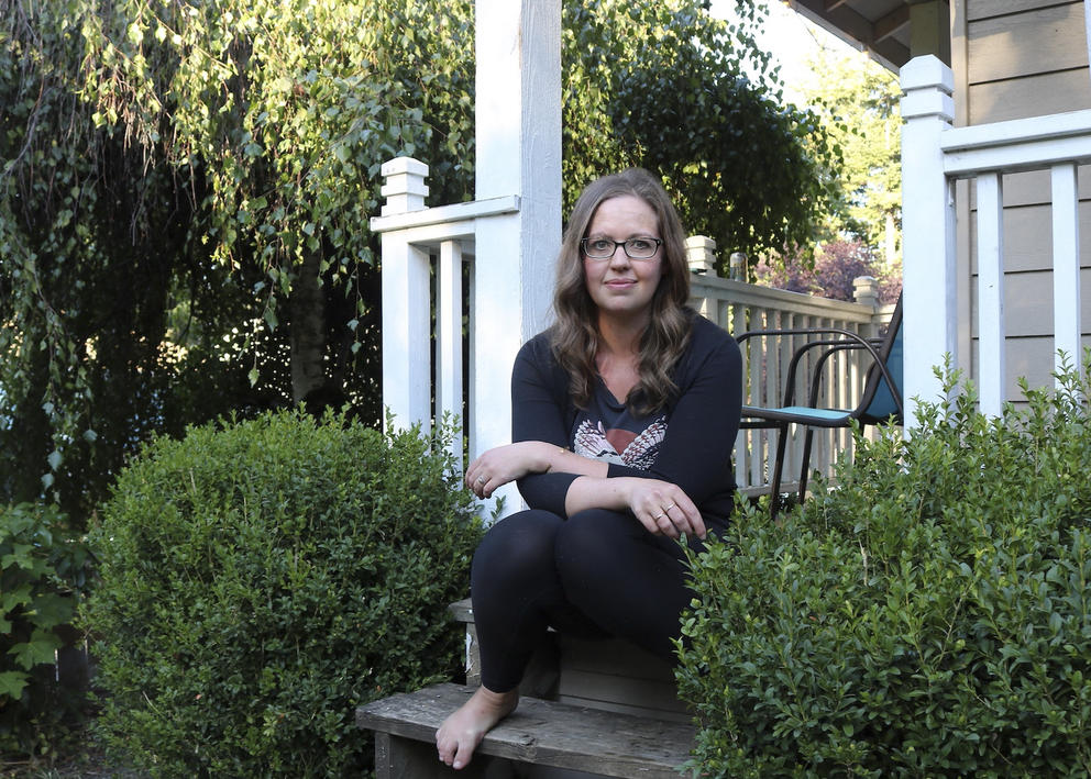 A woman seated on the porch of a house