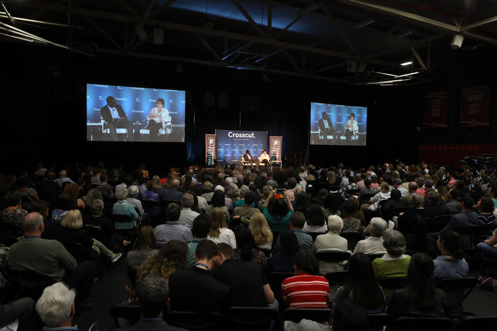 A crowd watches a journalist conduct an interview onstage