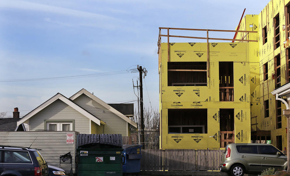 a single family home next to an unfinished multi-family home construction project