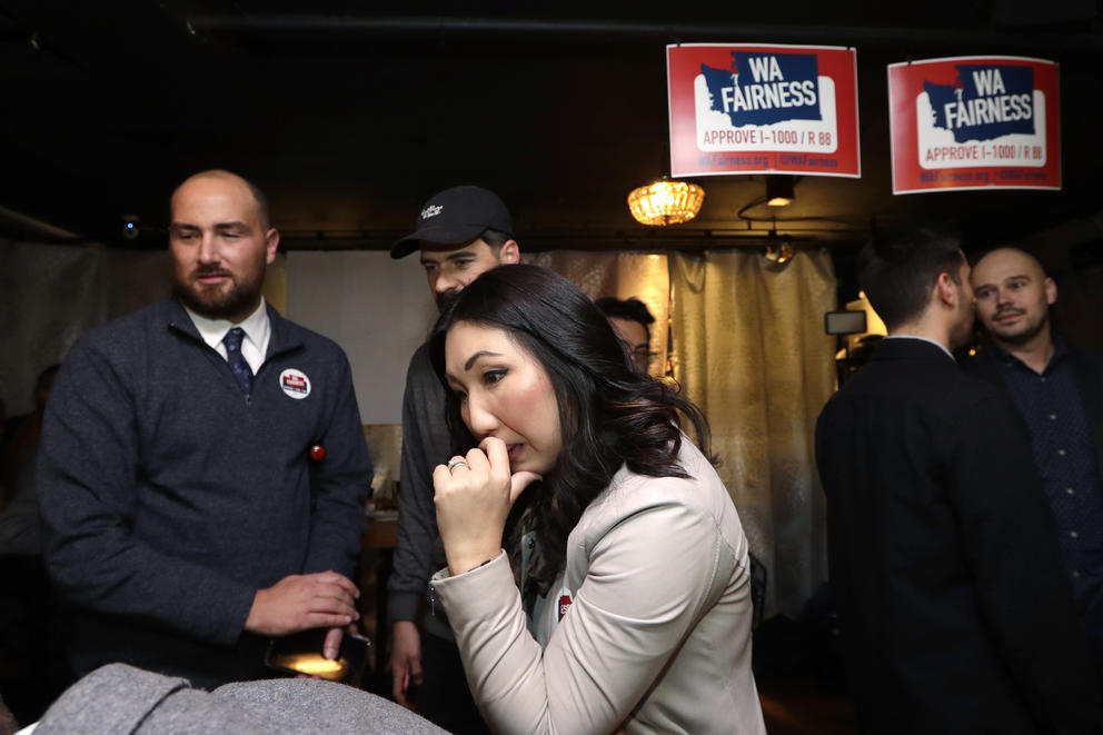 Kim watches a monitor for election results in a crowd of supporters