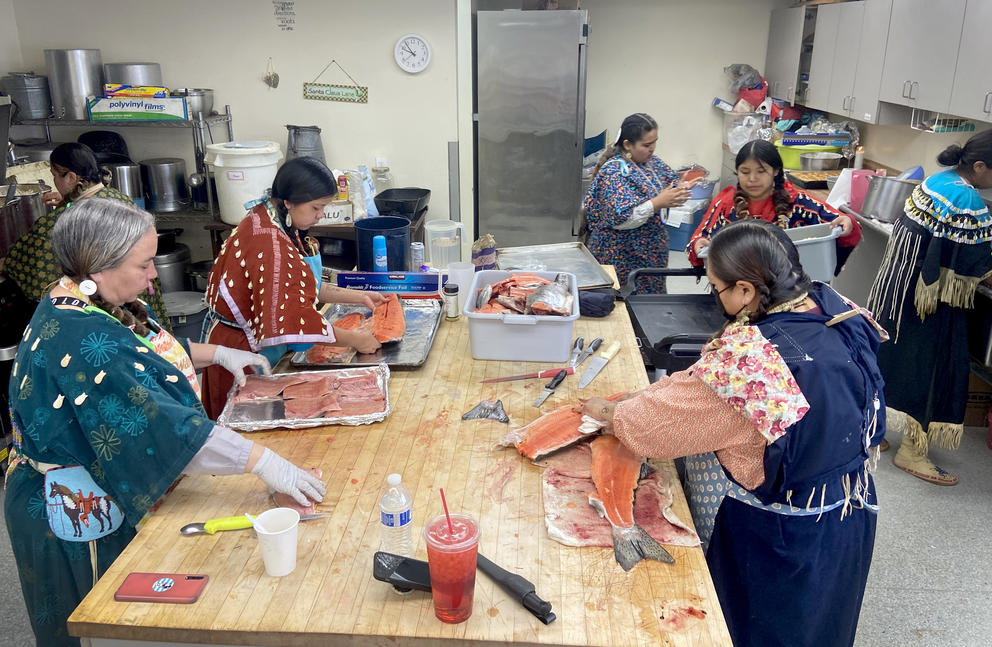 Women clean and filet salmon on a countertop